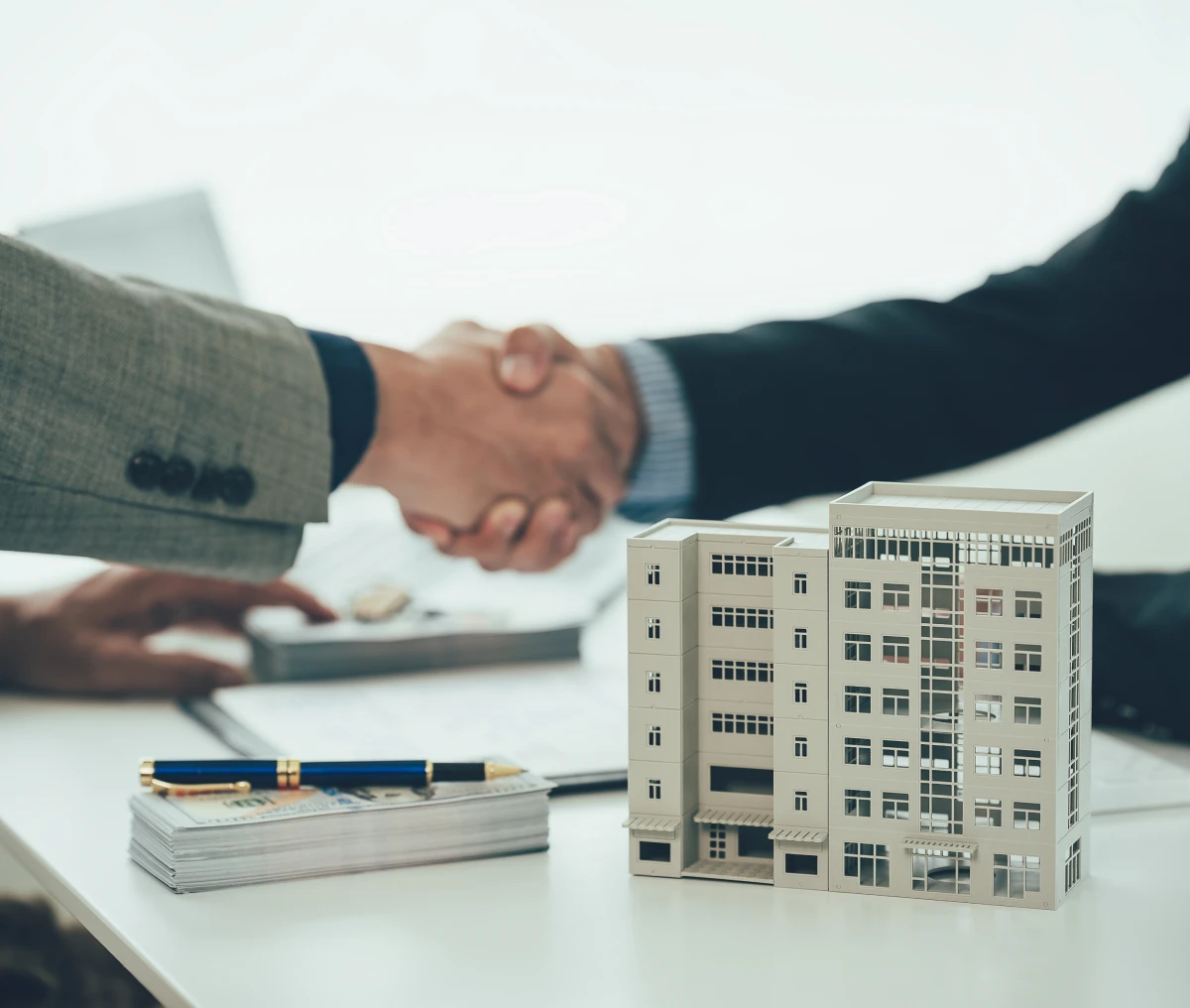 Business handshake over real estate model